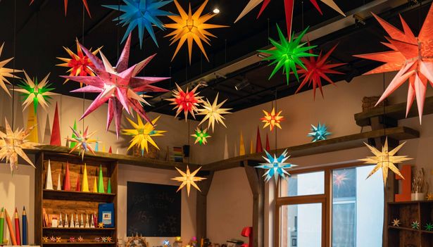 Children are sitting around a wooden table putting together small Moravian Stars