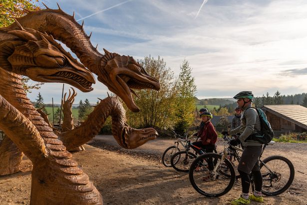 Ore Mountains Blockline wooden figures A family with their bikes looking at wooden dragon figures on the Blockline trail.